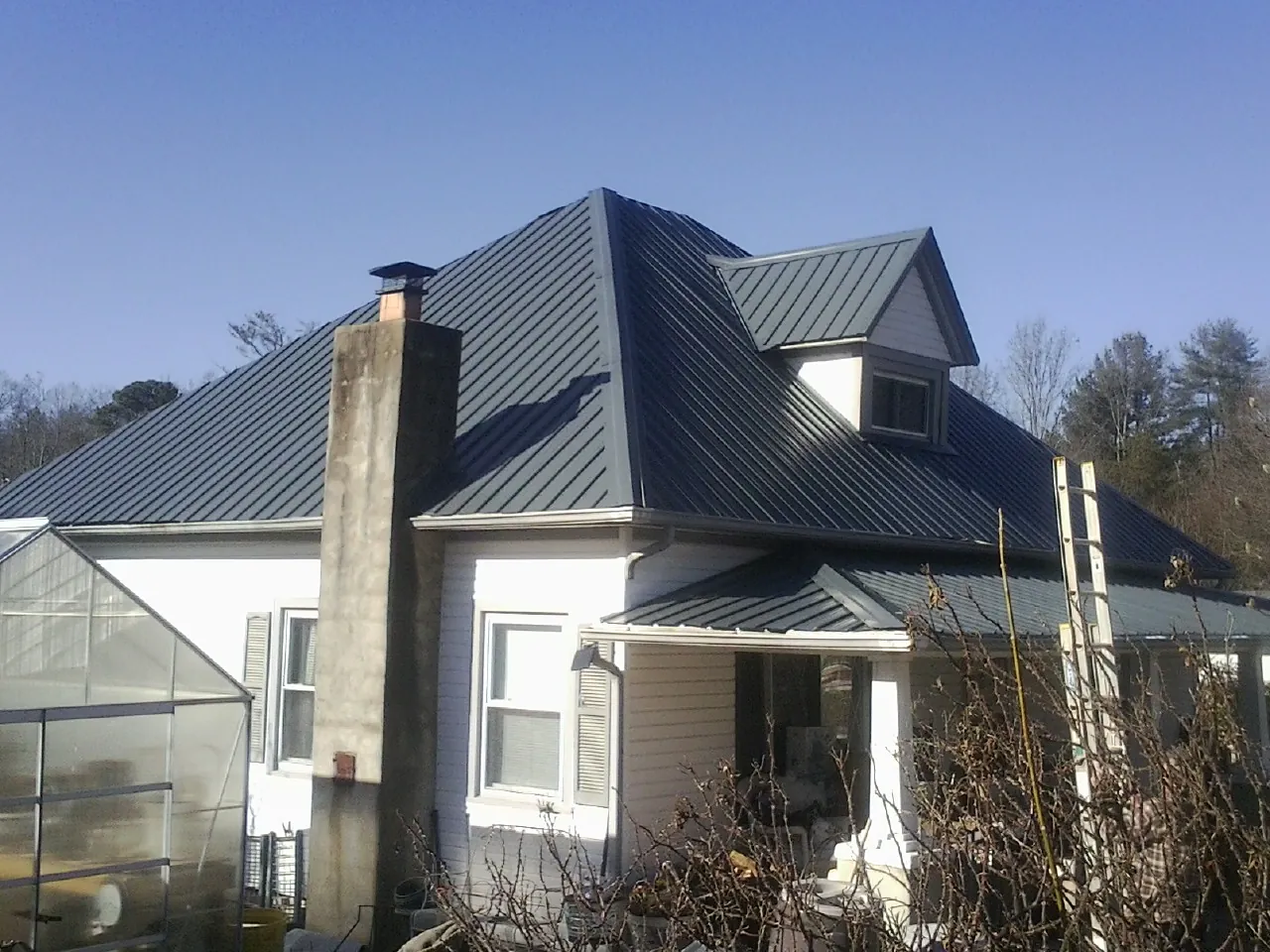 Dark blue standing seam metal roof on a white farmhouse with dormer — Slate & Tile Roof Repair by Roofing Brothers in Camden Point
