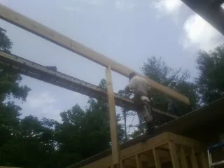 Carpenter setting a ridge beam over a new addition frame — Ice Dam Removal by Roofing Brothers in Camden Point