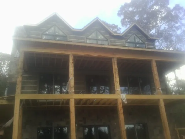Dormers and porch framing on a large log home under construction — Roof Coating work by our crew in Camden Point