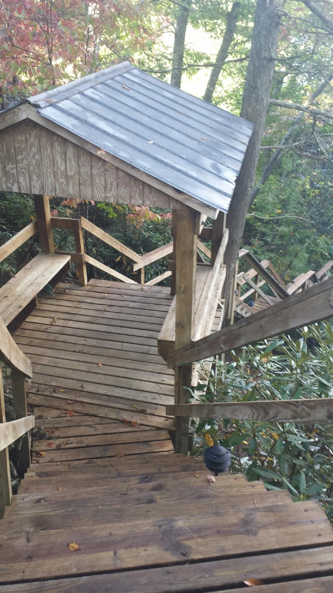 Metal roofed shelter over wooden steps on a wooded walkway — Skylight Repair & Installation work by our crew in Camden Point