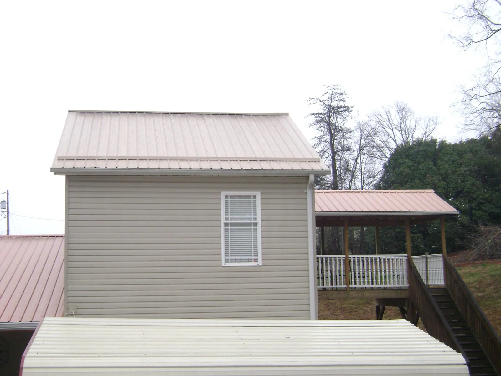 Tan metal roofs on a two story addition and attached porch, from a Roof Replacement job in Camden Point